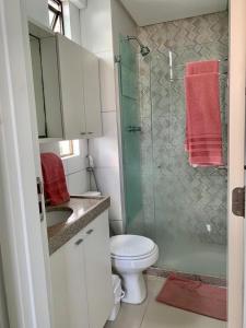 uma casa de banho com um WC e uma cabina de duche em vidro. em Apartamento com estilo e conforto no Recife