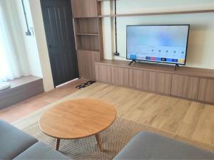 a living room with a table and a flat screen tv at Private Cozy Townhouse Near Lanmuang Village in Ban Pa Kluai