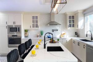 uma cozinha com um grande balcão branco com cadeiras pretas em Chic, Spacious Newmarket Home off Yonge St em Newmarket