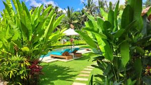 un jardín con piscina y exuberantes plantas verdes en TAMAN EDEN COTTAGE en Ubud