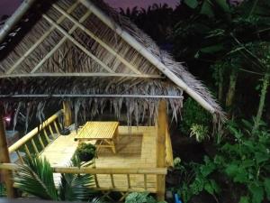 a hut with a wooden deck with a table at Rak Suan Homestay รักสวนโฮมสเตย์ in Khao Lak