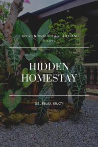 a sign that reads hidden homesery in front of a plant at Hidden Homestay in Marang
