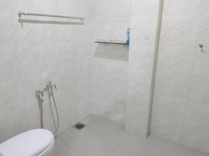 a white bathroom with a shower and a toilet at Hidden Homestay in Marang