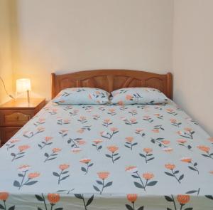 a bed with a blue blanket with orange flowers on it at Hidden Homestay in Marang