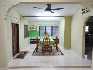 a dining room with a table and a ceiling fan at Hidden Homestay in Marang