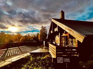 ein Haus mit einer Terrasse mit Sonne im Hintergrund in der Unterkunft Cozy cottage in central Beitostølen with Sauna in Beitostøl