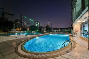a large swimming pool on top of a building at night at ALH Vacay - Modern studio vacation home in Dubai