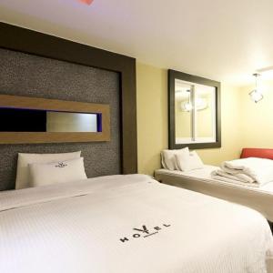 a hotel room with two beds and a mirror at v motel in Busan