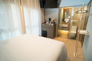 a bedroom with a white bed and a bathroom at Hotel Bencoolen at Hong Kong Street in Singapore