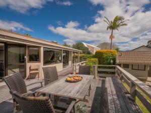 a wooden table and chairs on a deck with a fire pit at Relax On Courtney - Pauanui Holiday Home in Pauanui