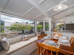a dining room with a table and chairs and a large window at Relax On Courtney - Pauanui Holiday Home in Pauanui
