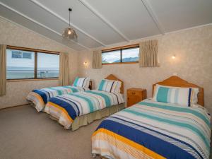 two beds in a room with two windows at Relax On Courtney - Pauanui Holiday Home in Pauanui