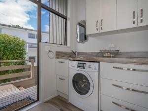 a kitchen with a washing machine and a balcony at Relax On Courtney - Pauanui Holiday Home in Pauanui