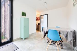 a room with a table and blue chairs at Les pins de Talant , au calme en rez de jardin in Talant