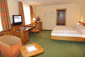 a hotel room with a bed and a desk and a television at Pension Hochleitner am Schloßpark in Tamsweg