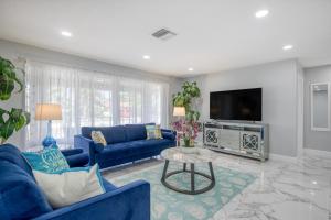 uma sala de estar com um sofá azul e uma televisão em Deerfield Beach in Style em Deerfield Beach