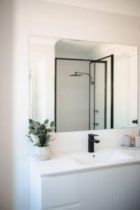 a white bathroom with a sink and a mirror at Seagrass in Culburra Beach