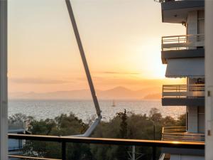 Flisvos Elite Seafront Luxury Apartment في أثينا: اطلالة على المحيط وقت الغروب من المبنى
