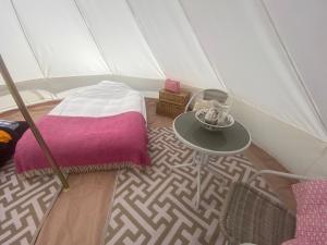 Charlton End Bell Tent في Charlton: غرفة بسرير وطاولة في خيمة