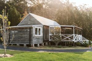 mały drewniany dom z gankiem i drzewem w obiekcie Picturesque Barn located on the Shoalhaven River w mieście Nowra