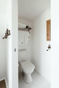 a white bathroom with a toilet in a room at Picturesque Barn located on the Shoalhaven River in Nowra