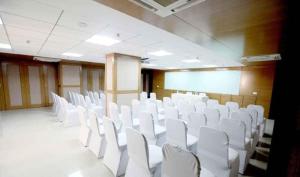 a conference room with white chairs and a white board at Hotel DORTN in Pune