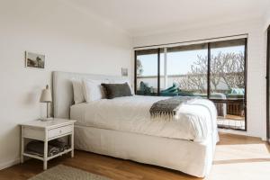 a white bedroom with a bed and a large window at The G At Gerroa in Gerroa