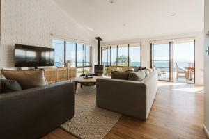 a living room with two couches and a flat screen tv at The G At Gerroa in Gerroa