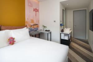 Jono Bangkok Asok Hotel في بانكوك: غرفة نوم بسرير ابيض عليها دبدوب