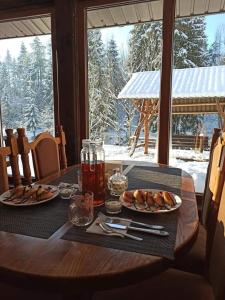 - une table en bois avec deux assiettes de nourriture et une boisson dans l'établissement Zatishok Bilya Richky, à Pilipets