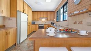 a large kitchen with wooden cabinets and a white refrigerator at The Callala Hideaway in Callala Beach