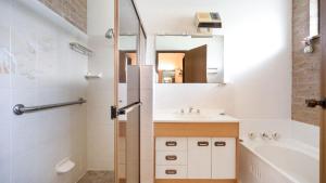a bathroom with a sink and a tub and a mirror at The Callala Hideaway in Callala Beach
