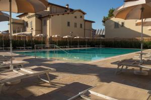 a swimming pool with chairs and umbrellas next to a building at Villa Carobbi Apartments Florence in Florence