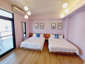 2 łóżka w pokoju z różowymi ścianami i drewnianą podłogą w obiekcie Summer Dream w mieście Magong