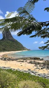 a beach with a view of the ocean and a mountain at Maré suites in Fernando de Noronha