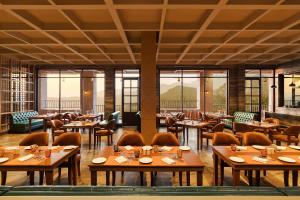 restauracja z drewnianymi stołami, krzesłami i oknami w obiekcie Welcomhotel By ITC Hotels, Jim Corbett w mieście Marchula