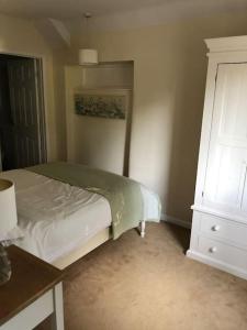 a bedroom with a white bed and a dresser at The Grooms Den @ Grove Farm in Fenny Compton