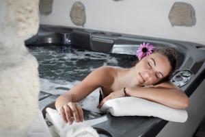 Una donna sdraiata in una vasca da bagno con un fiore in testa di Hotel Scoiattolo a Baselga di Pinè