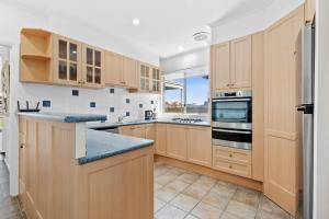 a kitchen with wooden cabinets and a large window at All Beached Out - 8 guests, cental, 450m to beach! in Ocean Grove