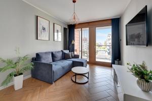 a living room with a blue couch and a table at Downtown Apartments Aura - Riverside & Parking in Gdańsk