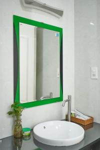 een badkamer met een wastafel en een groene spiegel bij Pooh House 3 - Sea breeze in Vung Tau