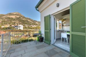 uma varanda com portas verdes e uma cozinha com uma mesa em Il Quartiere apt Capraia em Pomonte