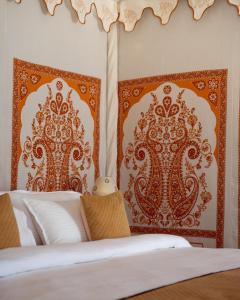 a bedroom with a bed with orange and white headboards at Real Desert Man Safari Camp in Jaisalmer