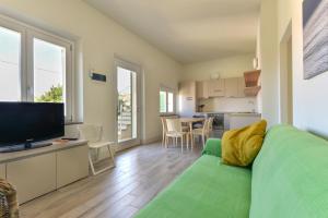 Il Quartiere apt Giglio في بومونته: غرفة معيشة مع أريكة خضراء ومطبخ