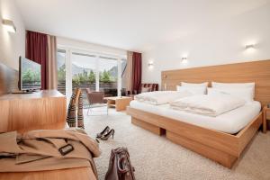 a hotel room with two beds and a desk at Alpen-Comfort-Hotel Central in Nauders