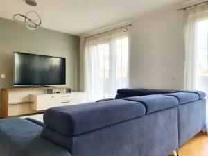 Il comprend un salon doté d'un canapé bleu et d'une télévision à écran plat. dans l'établissement Near Lake Spacious & Furnished Beautiful Apartment, à Vienne