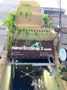 a sign on the side of a building with plants at Hanoi EcoStay 2 hostel in Hanoi