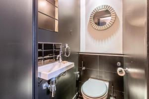 La salle de bains est pourvue de toilettes, d'un lavabo et d'un miroir. dans l'établissement Sublim by Sweet Inn, à Paris