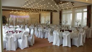 a banquet hall with white tables and chairs and chandeliers at Waldhotel Schäferberg in Espenau