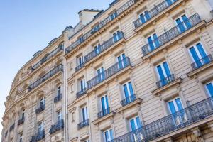 - un bâtiment en paris avec des fenêtres et des balcons bleus dans l'établissement Sublim by Sweet Inn, à Paris